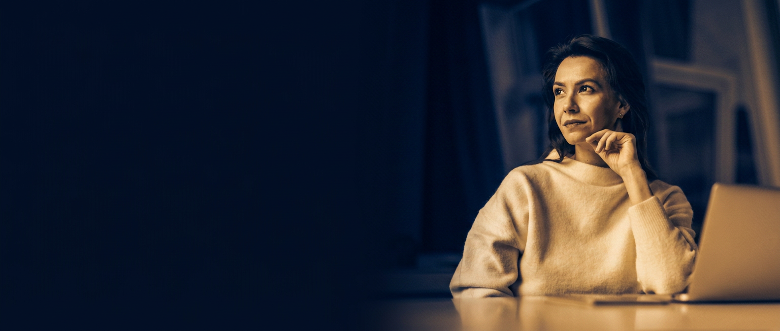 An analyst working late at a laptop, reviewing deal material